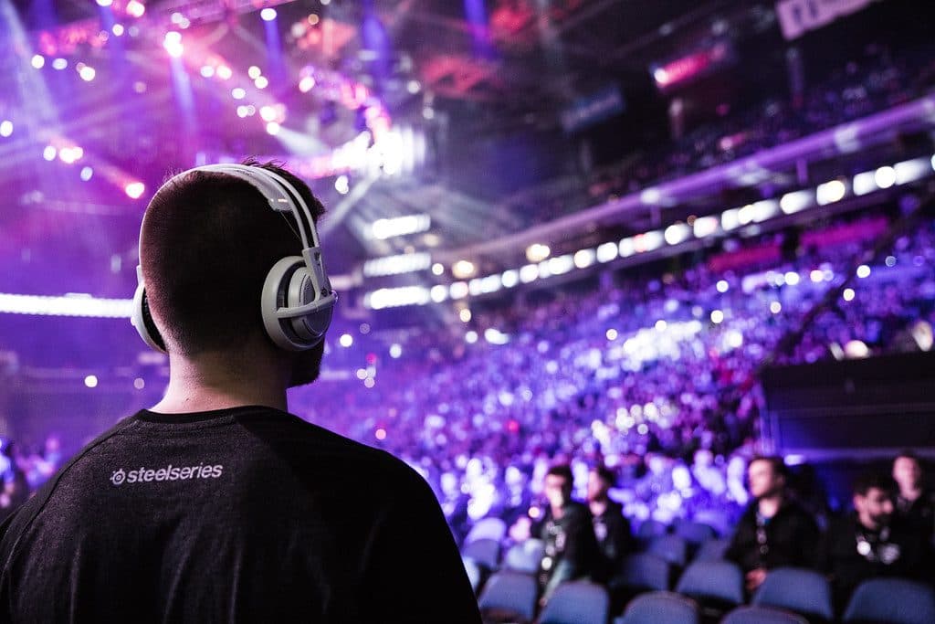 Spectator in headphones watching a packed esports arena